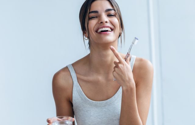 xylitol tandpasta bij lachende vrouw met tandenborstel